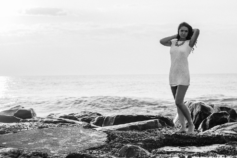 Kaitlyn posing on rock at Asbury Park beach for Senior Photos with Kasey Ivan Photography