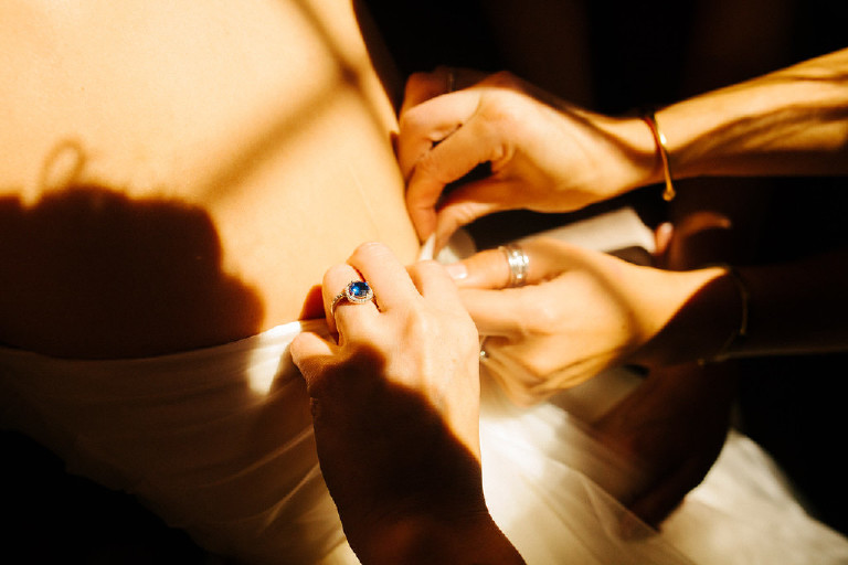 nimble hands fasten the back of the wedding dress at Chimney Hill Estate wedding in Lambertville NJ