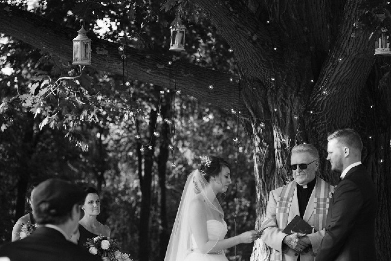 black and white photo of bride reading vows in front of tree at Chimney Hill Estate wedding ceremony in Lambertville NJ by Kasey Ivan Photography