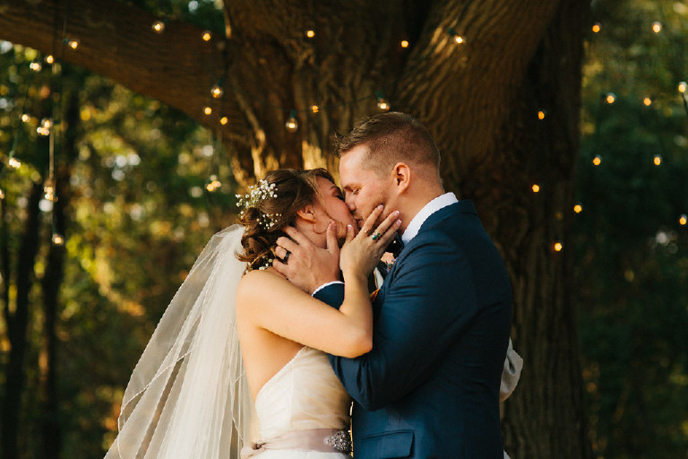 bride and groom kiss in front of large tree during Chimney Hill Estate wedding ceremony in Lambertville NJ by Kasey Ivan Photography
