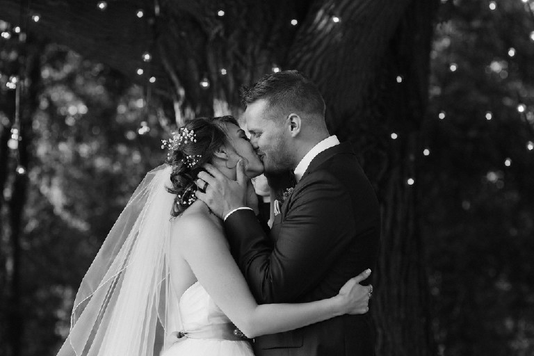 bride and groom kiss in front of big tree during Chimney Hill Estate wedding ceremony in Lambertville NJ by Kasey Ivan Photography