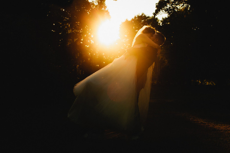 sunset as groom holds bride in air for kiss at Chimney Hill Estate wedding in Lambertville by Kasey Ivan Photography