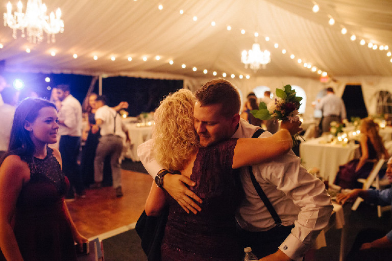 groom hugs guest under canopy tent at Chimney Hill Estate wedding reception by Kasey Ivan Photography
