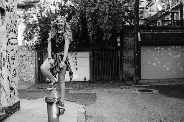 standing on fire hydrant outside Magic Garden South Street in Philadephia for senior photos by Kasey Ivan Photography