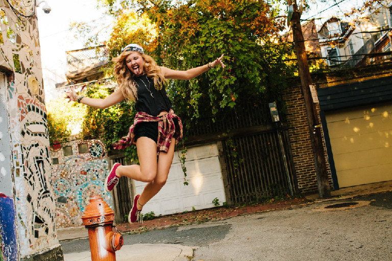 rock and roll jump off of hydrant outside Magic Garden South Street in Philadephia for senior photos by Kasey Ivan Photography