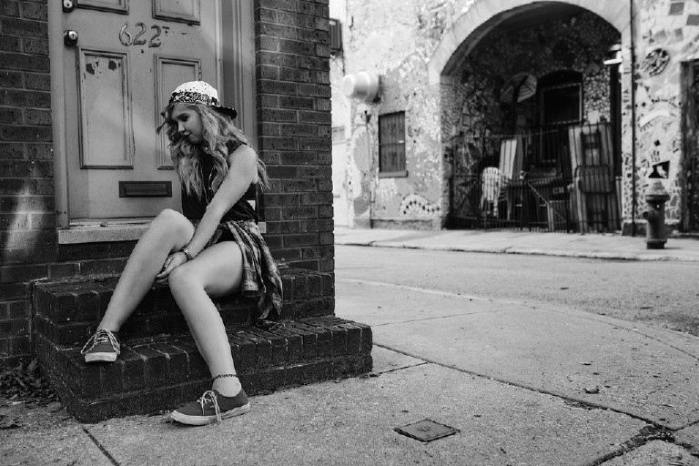 sitting on ledge outside Magic Garden South Street in Philadephia for senior photos by Kasey Ivan Photography
