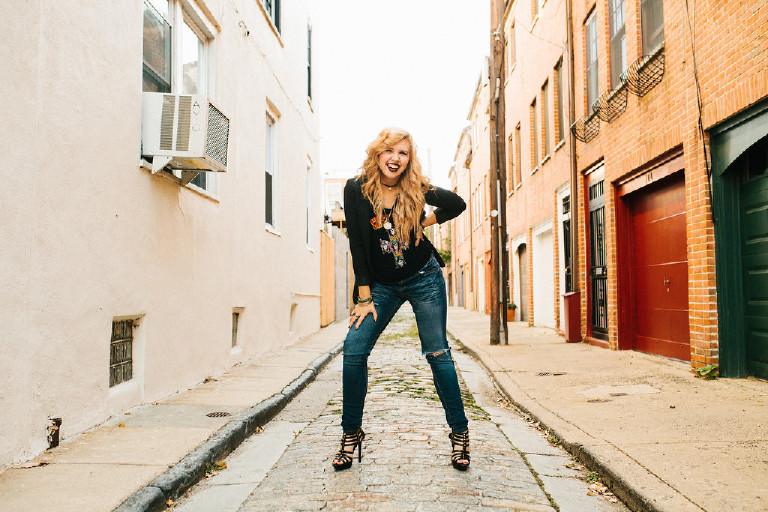 Kassi smiling and laughing in downtown Philadelphia sidestreet for senior photos by Kasey Ivan Photography
