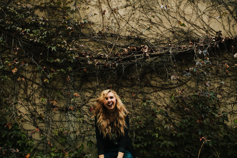 laughing next to ivy wall in downtown Philadelphia for senior photos by Kasey Ivan Photography