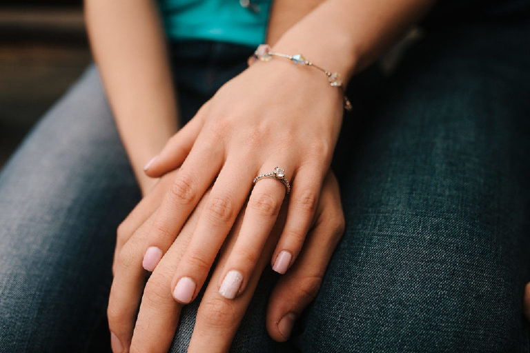 Couple holds hands and shows off engagement ring