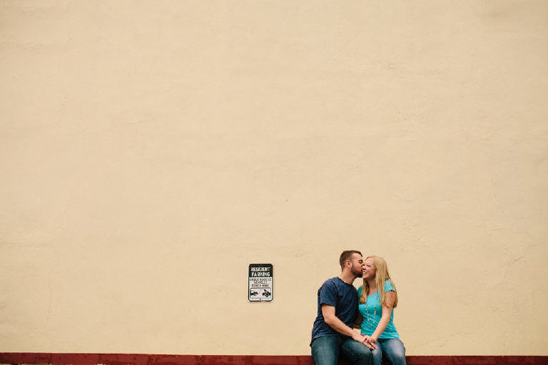 Couple kissing on ledge outside Bond Street Bar for engagement photos in Asbury Park NJ by Kasey Ivan Photography