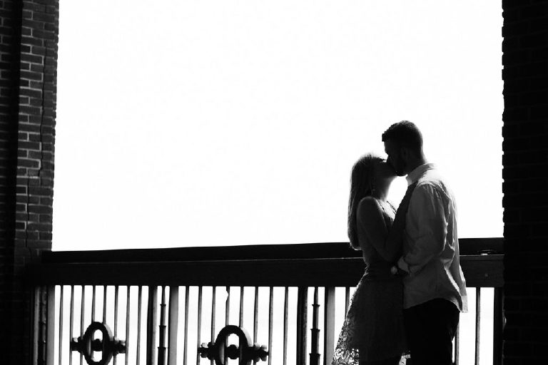 Black and white high contrast silhouette of couple kissing on a balcony