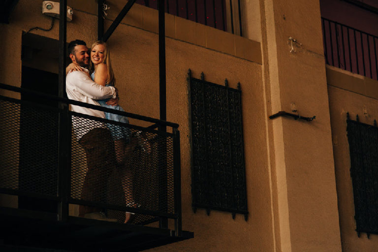 Dark balcony fire escape with couple smiling for engagement photos at Asbury Park