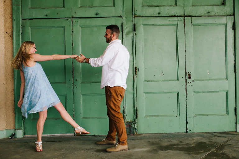 Couple dances in front of rustic green doors on the Jersey Shore for engagement photos