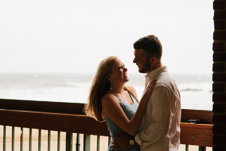 View of Asbury Park beach as couple holds each other for engagement photos