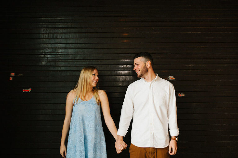 Jenna and Ryan holding hands in front of black garage doors at the Jersey Shore