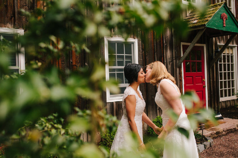 brides kiss through the ivy before LGBT same sex wedding at 1740 House outside New Hope PA by Kasey Ivan Photography