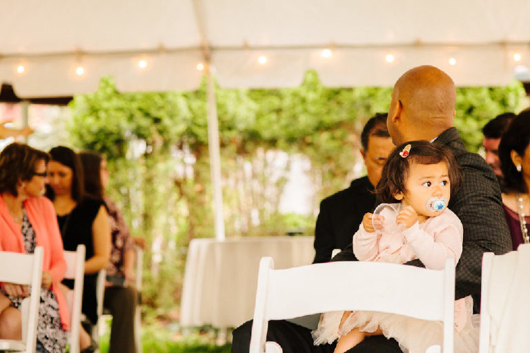 young Filipina girl looks on with a pacifier before a same sex wedding on the Delaware River
