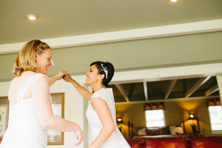 two young lesbian brides laugh while dancing in their room at the 1740 House before their same sex wedding by Kasey Ivan Photography