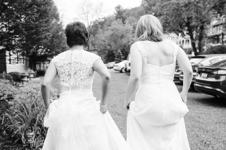 brides holding wedding dresses together while walking in parking lot