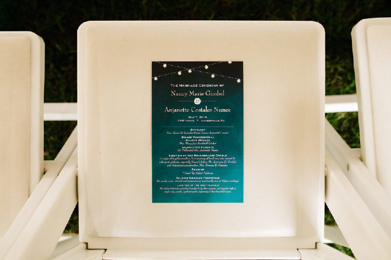 ceremony bulletin placed on a white chair before a same sex wedding at 1740 House outside New Hope PA