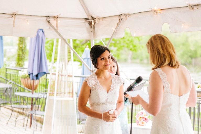 bright sunlit photo on patio overlooking the Delaware River as bride recites her vows at the 1740 House