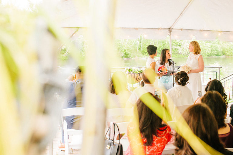 unique vantage point of lesbian bridal couple standing during their ceremony at a rustic Delaware River wedding