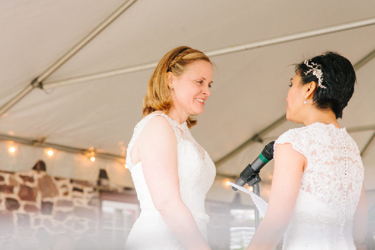 bright sunlit photo on patio overlooking the Delaware River as bride recites her vows at the 1740 House