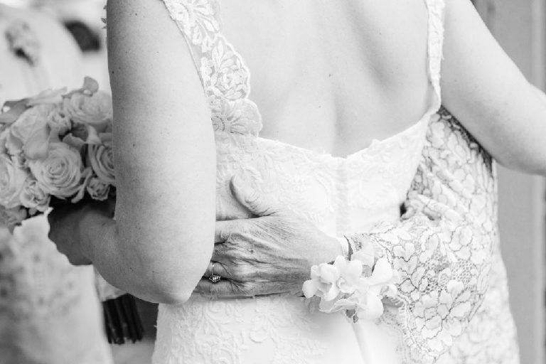 intimate shot of mothers arm around her daughter the bride before a wedding ceremony
