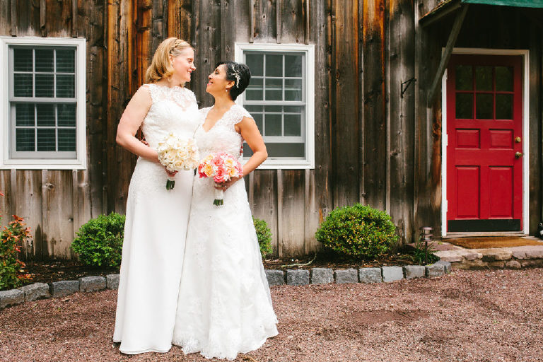 same sex wedding brides embrace outside the unfinished wood of 1740 House outside New Hope PA by Kasey Ivan Photography