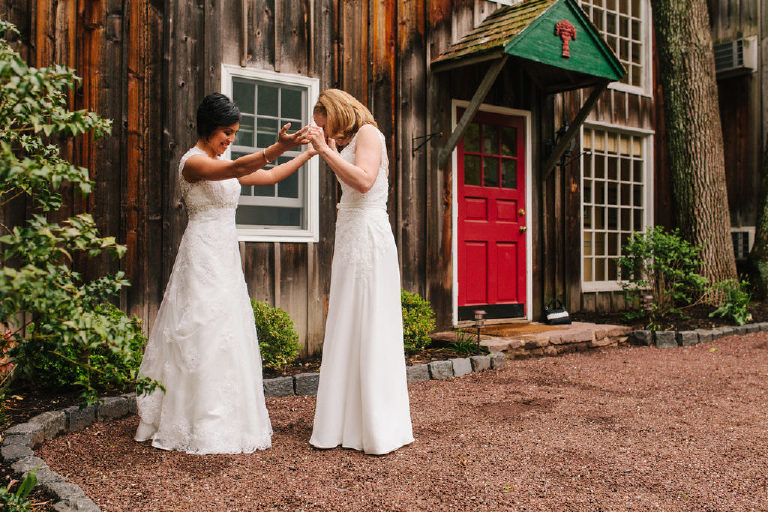 brides look at dresses next to a red door at a lesbian wedding at 1740 House outside New Hope PA