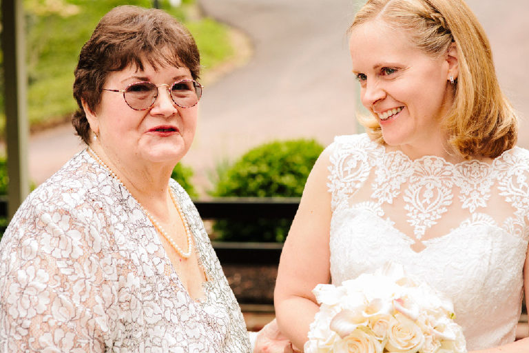 mother of the bride looks on as bride smiles before wedding ceremony