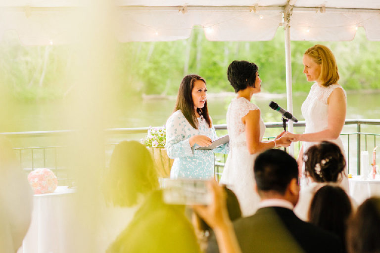 brides hold hands as ceremony concludes overlooking the Delaware River at the 1740 House by Kasey Ivan Photography