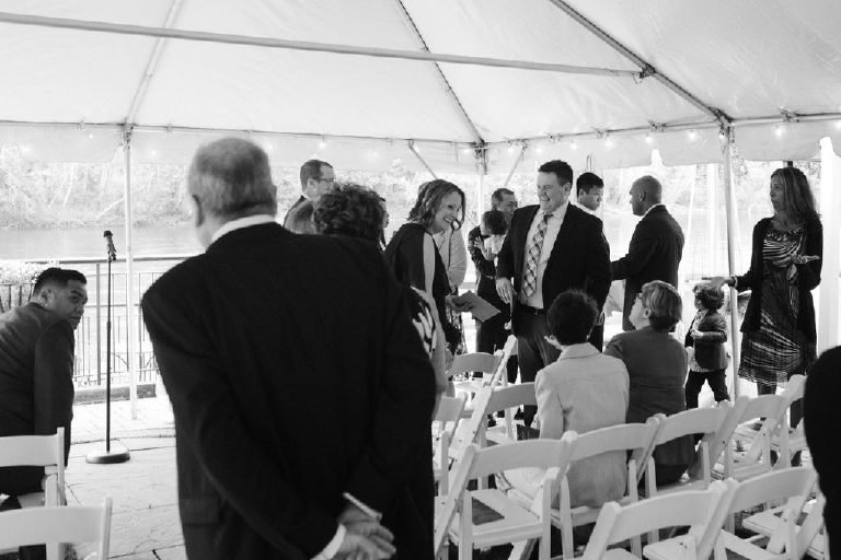 family and friends of the brides arrive and begin to take their seats inside the tent at 1740 House with a view of the Delaware River