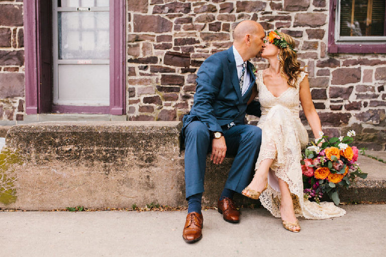 bride and groom kiss for summer wedding portraits outside a historic stone building near the Lumberville foot bridge over the Delaware River by Kasey Ivan Photography outside the Black Bass Hotel near New Hope PA