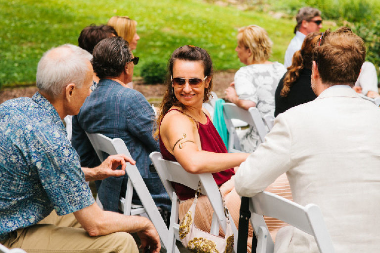 summer wedding guest with sunglasses and armband speaks with other guests