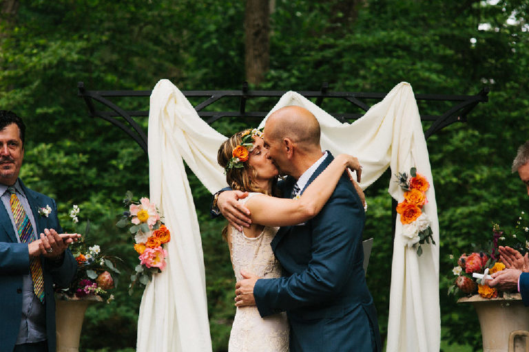 bride and groom kiss at summer wedding ceremony in the woods at Black Bass Hotel outside New Hope Pennsylvania by Kasey Ivan Photography