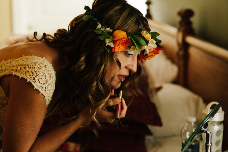 italian bride in flower crown applies last minute touches to makeup before wedding by Kasey Ivan Photography