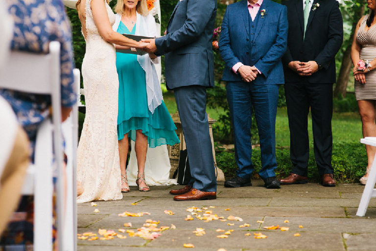 view of the bride and grooms hands next to rose flower petals at the Black Bass Hotel outside New Hope PA
