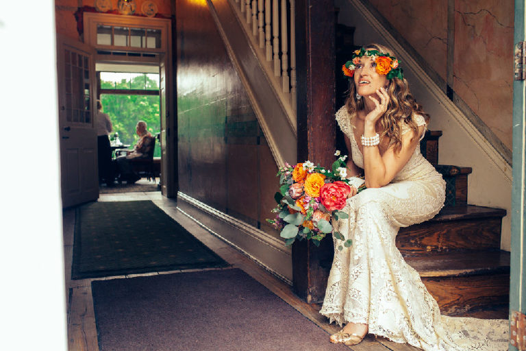 bride in a flower crown sits after a summer wedding on the stairs inside the entrance to the Black Bass Hotel near New Hope PA by Kasey Ivan Photography