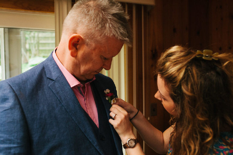 best man gets a boutonnière pinned on him by the events coordinator of the Black Bass Hotel