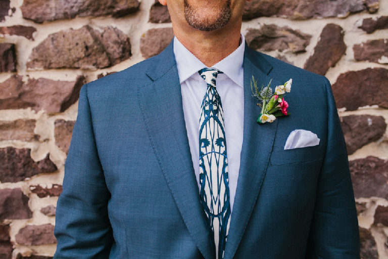 close up of fashion designer tie and grooms blue suit on a stone wall by Kasey Ivan Photography