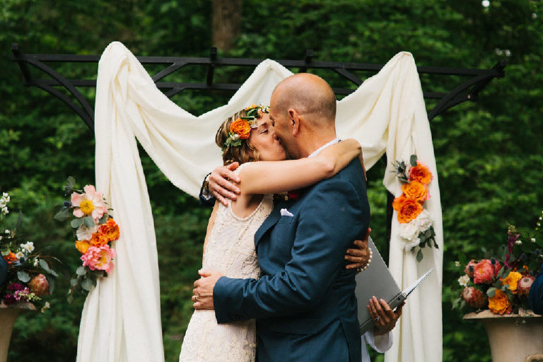 bride and groom kiss at summer wedding ceremony in the woods at Black Bass Hotel outside New Hope Pennsylvania by Kasey Ivan Photography