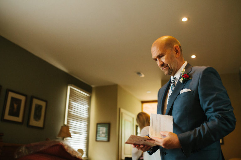 groom in a blue suit reads his handwritten vows before a wedding ceremony at the Black Bass Hotel