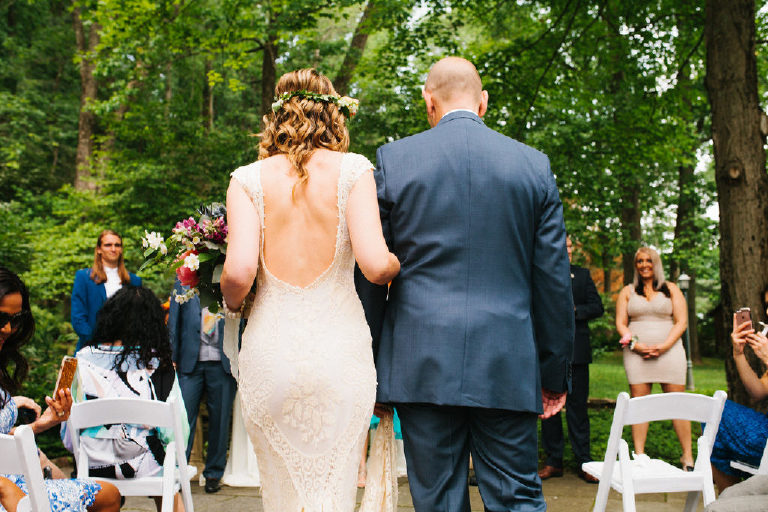 backside view of bride and groom walking arm and arm down the aisle to their ceremony at the Black Bass Hotel outside New Hope Pennsylvania