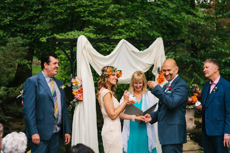 bride and groom laughing at summer wedding ceremony in the woods