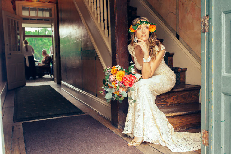 bride in a flower crown sits after a summer wedding on the stairs inside the entrance to the Black Bass Hotel near New Hope PA by Kasey Ivan Photography