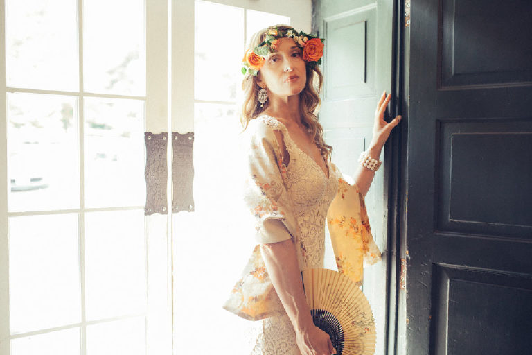 bride with paper fan stands inside the entrance to the Black Bass Hotel near New Hope PA by Kasey Ivan Photography