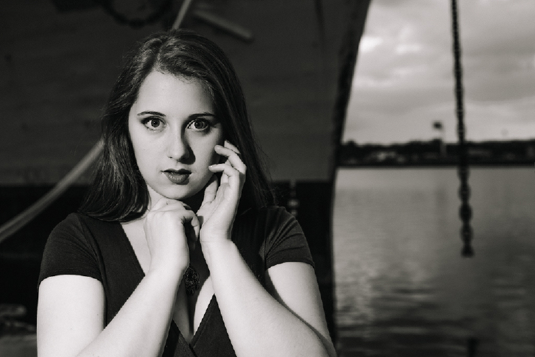 Black and white photograph of a senior girl posing dramatically framing her face with her hands for Kasey Ivan Photography