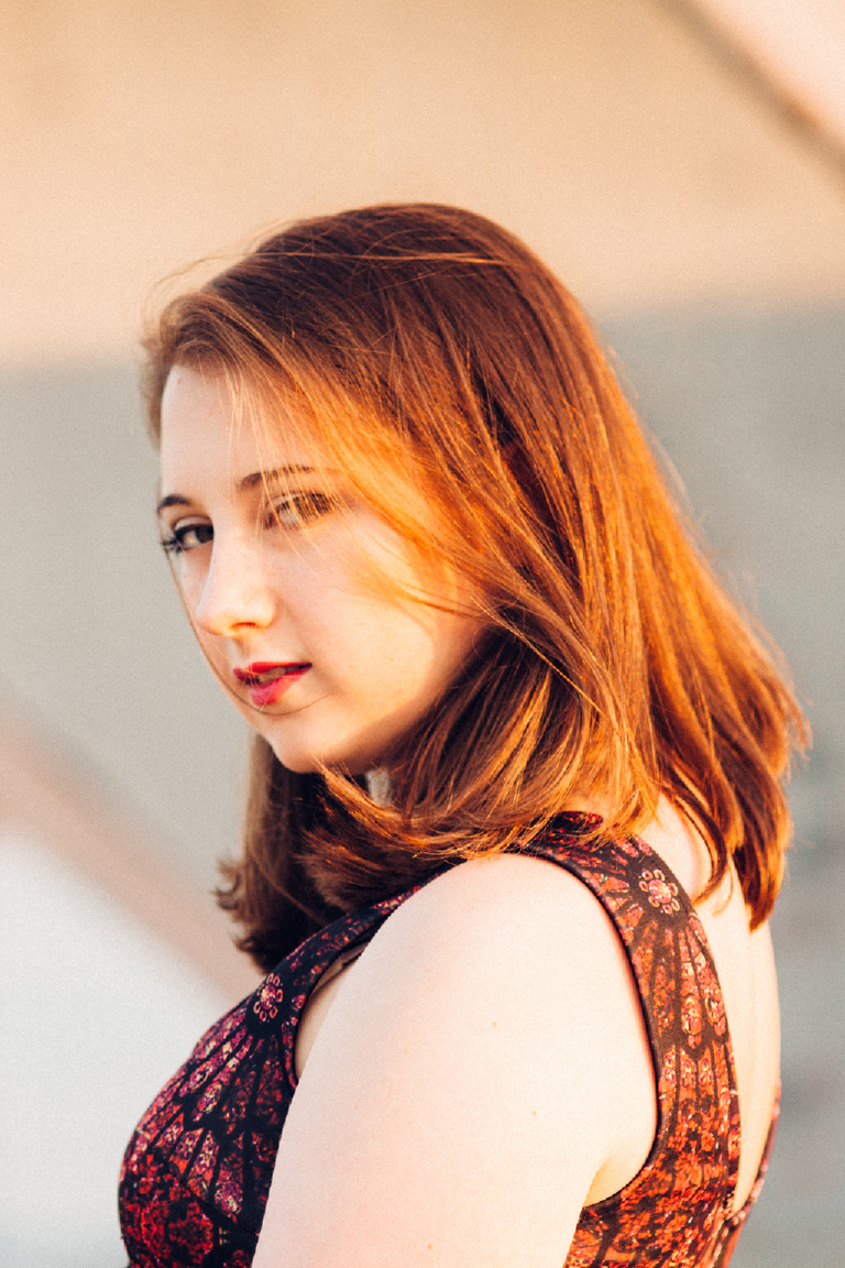 Senior girl looking over her shoulder posing for Kasey Ivan Photography at the navy shipyard in Philadelphia
