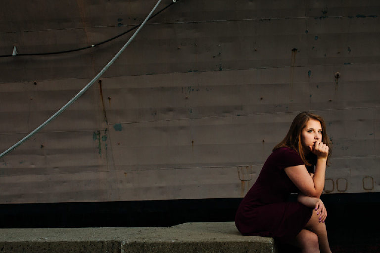 Senior girl sitting and thinking infront of a boat at the navy shipyard in philadelphia PA